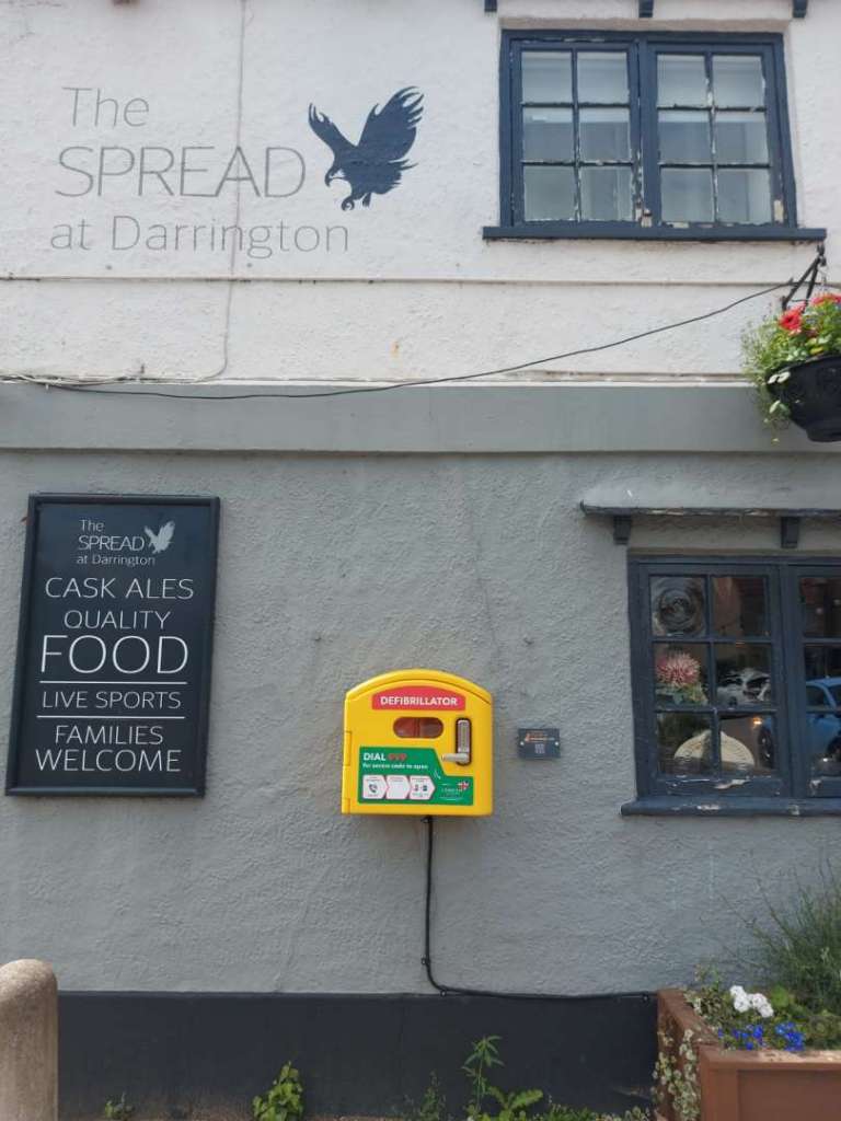 Image of the defibrillator on the wall of the Spread 1
